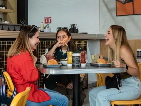 Three friends laughing over lunch at a cafe table