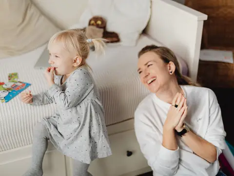 A mother laughing with her toddler daughter at home